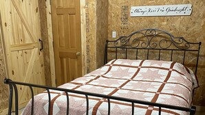 Una estructura de cama metálica con una colcha estampada, una puerta de madera y una pared decorada con papel de construcción.