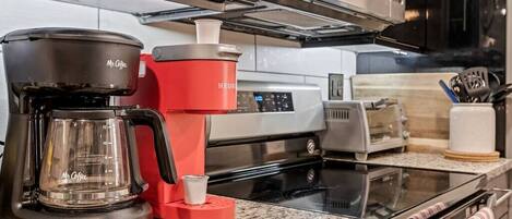 A kitchen with a coffee maker, toaster, and oven.