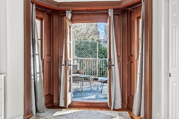An open bay window with a view of a patio area, including a table and chairs.