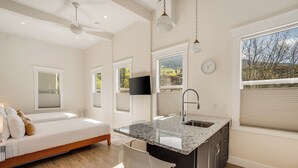 A modern kitchen with a granite countertop, a built-in sink, and a large window offering a view of trees. - Stirling All Suites Hotel (Nelson)