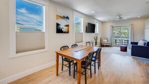 A spacious living area with a wooden dining table, black chairs, a blue sofa, and large windows offering views of the outdoors. - Stirling All Suites Hotel (Nelson)