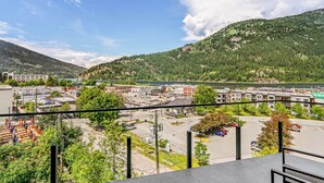 A view from a balcony overlooking a parking lot, a river, and a town with buildings and mountains in the background. - Stirling All Suites Hotel (Nelson)