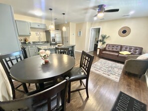 Eine moderne Küche mit Essbereich, ein Wohnzimmer mit Sofa und Deckenventilator.