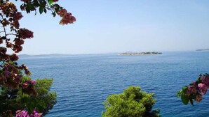 A coastal view with a clear blue sea, a distant island, and lush greenery. - Remarkable 2-bed Apartment in Tribunj, Best View (Tribunj)