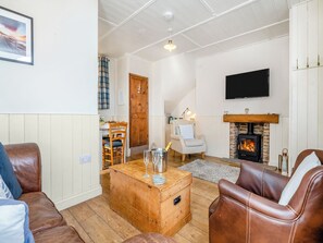 A living room with a fireplace, leather sofas, a wooden coffee table, and a television mounted on the wall.
