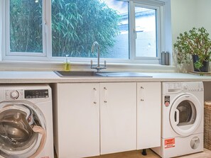 A laundry area with a washing machine, a dryer, and a sink with a window above.
