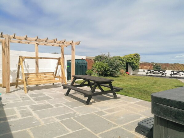 A patio with a swing set, picnic table, and outdoor seating area.