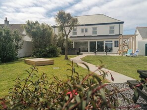 Une maison à deux étages avec un patio, une balançoire et une pelouse.