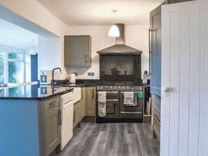 A compact kitchen with a built-in oven, a coffee maker, and a hanging light fixture.