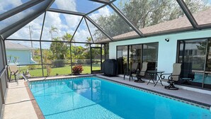 Une piscine couverte avec un espace patio, des sièges extérieurs et une vue sur le paysage environnant.