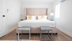 Een moderne slaapkamer met een groot bed, twee nachtkastjes en een raam met jaloezieën.