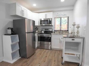 Fully equipped kitchen with modern appliances, a window, and storage cart.