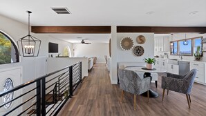 A spacious kitchen with white cabinets, a dining area with patterned chairs, and a view of the outdoors. - Nestled in the beautiful desert of Tucson, this home will take your breath away. (Tucson)