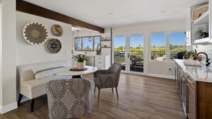 A spacious kitchen with a central island, a dining area with a round table and two patterned chairs, and a view of a balcony with outdoor furniture. - Nestled in the beautiful desert of Tucson, this home will take your breath away. (Tucson)