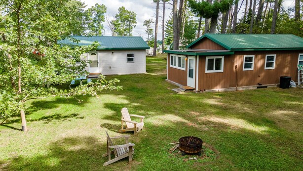 Un camping con dos cabañas, una fogata y una mesa de picnic.