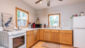 Una cocina con armarios de madera, una estufa blanca, un refrigerador y una ventana.