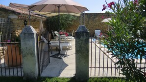Une cour arrière clôturée avec une piscine, du mobilier d’extérieur et un mur en pierre.