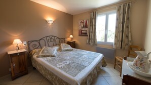 Une chambre à coucher avec un lit, des tables de chevet, une chaise et une fenêtre avec des rideaux.