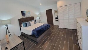 Une chambre à coucher moderne avec un lit, des tables de chevet, une armoire et un tableau au mur.