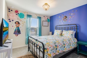 A bedroom with a bed, a TV, and a window with curtains.
