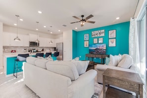 A modern kitchen with white cabinets, a microwave, and a ceiling fan.