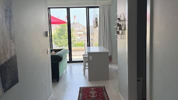 A modern interior with a bench, a red patterned rug, and a view through a glass door to an outdoor area with a red umbrella.