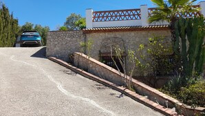 A house with a stone facade, a tiled roof, and a paved driveway.