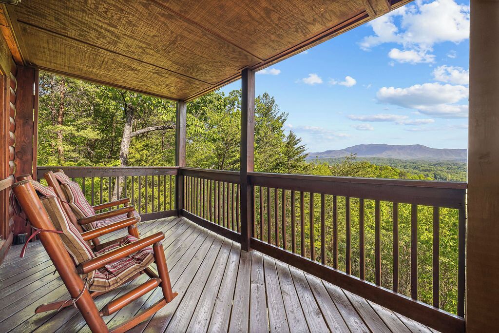 Une terrasse en bois dotée d’un espace abrité et offrant une vue sur un paysage montagneux.