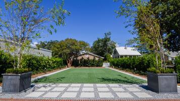 A well-maintained lawn with a paved walkway leading to a house with a white fence and a covered porch.