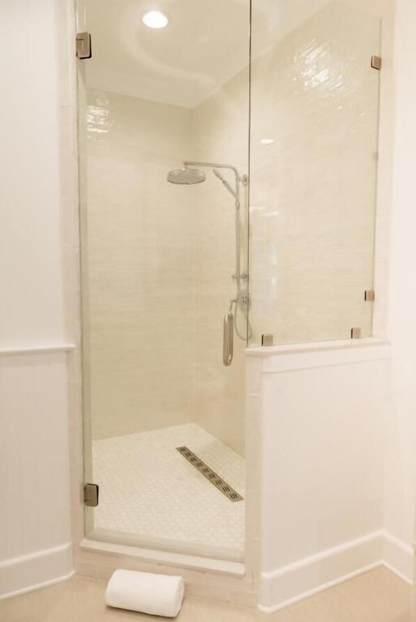 Ducha con cerramiento de vidrio, cabezal de ducha de mano y panel de control.