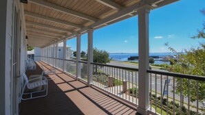 A covered outdoor area with white railings and a wooden ceiling, overlooking a body of water and a marina.