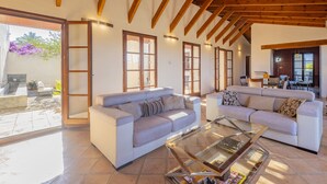Un salon spacieux avec deux canapés, une table basse en verre et des poutres en bois au plafond.