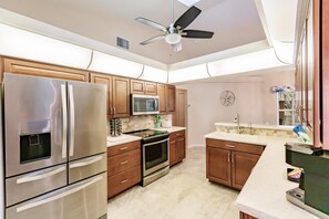Enjoy cooking in this well-equipped kitchen with a refrigerator, oven, and wooden cabinets.