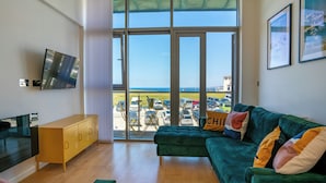 A modern living room with a green sofa, a yellow cabinet, and a TV on the wall. - 2 bedroom accommodation in Newquay (Newquay)