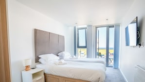 A hotel room with a large bed, a bedside table, a lamp, and a TV. - 2 bedroom accommodation in Newquay (Newquay)