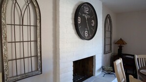 A room with a white brick fireplace, a large wall clock, and two arched windows. - Waterfront Parker Strip - Private 50' Dock - Moovalya Keys (Parker)