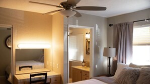 A hotel room with a bed, a desk with a chair, a vanity with a mirror, a ceiling fan, and a window with curtains. - Waterfront Parker Strip - Private 50' Dock - Moovalya Keys (Parker)
