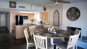 A modern kitchen with a central island, wooden cabinets, a built-in oven, and a dining area with a round table and chairs. - Waterfront Parker Strip - Private 50' Dock - Moovalya Keys (Parker)