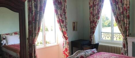 A bedroom with a bed, a desk, and a window with curtains.