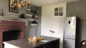 Eine Küche mit Kamin aus Ziegelsteinen, einem Edelstahl-Kühlschrank und einer Kristallleuchter.