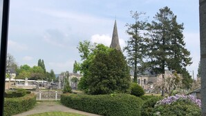 Ein Friedhof mit einem markanten Kirchturm, umgeben von gepflegten Hecken und Bäumen.