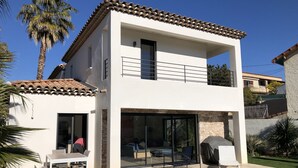 Ein zweistöckiges Haus mit Ziegeldach, Balkon und Swimmingpool.