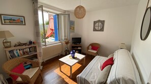Un accogliente soggiorno con divano, poltrone, tavolino, libreria, televisore e finestra con tende.