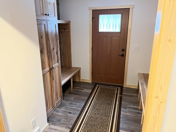 A hallway with a wooden door, a bench, and a wooden cabinet. - NEW 5BR Cabin (Wetmore)