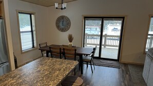 A kitchen with a large granite countertop, wooden chairs, a dining table, and a clock on the wall. - NEW 5BR Cabin (Wetmore)