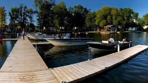 A wooden dock extending into calm water with boats moored at the end. - Grace Land Cottages (West Nipissing)