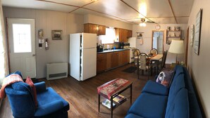 A compact living space with a kitchenette, dining area, and seating. - Grace Land Cottages (West Nipissing)