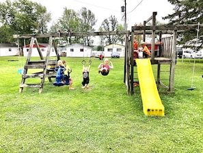 Une aire de jeux avec des balançoires, un toboggan et une structure d’escalade.