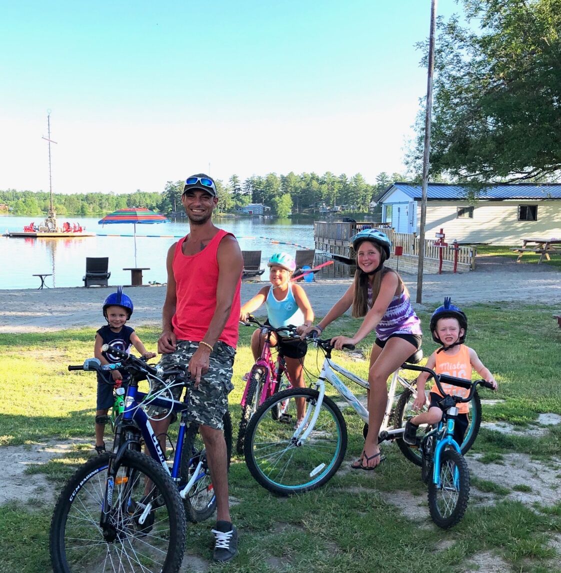 A family with bicycles near a lake with boats and a dock.