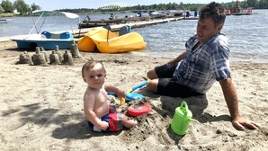 A sandy beach with a child and an adult. - Grace Land Cottages (West Nipissing)